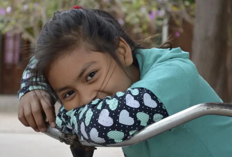Argentina Niña sonriendo apoyada en una bicicleta