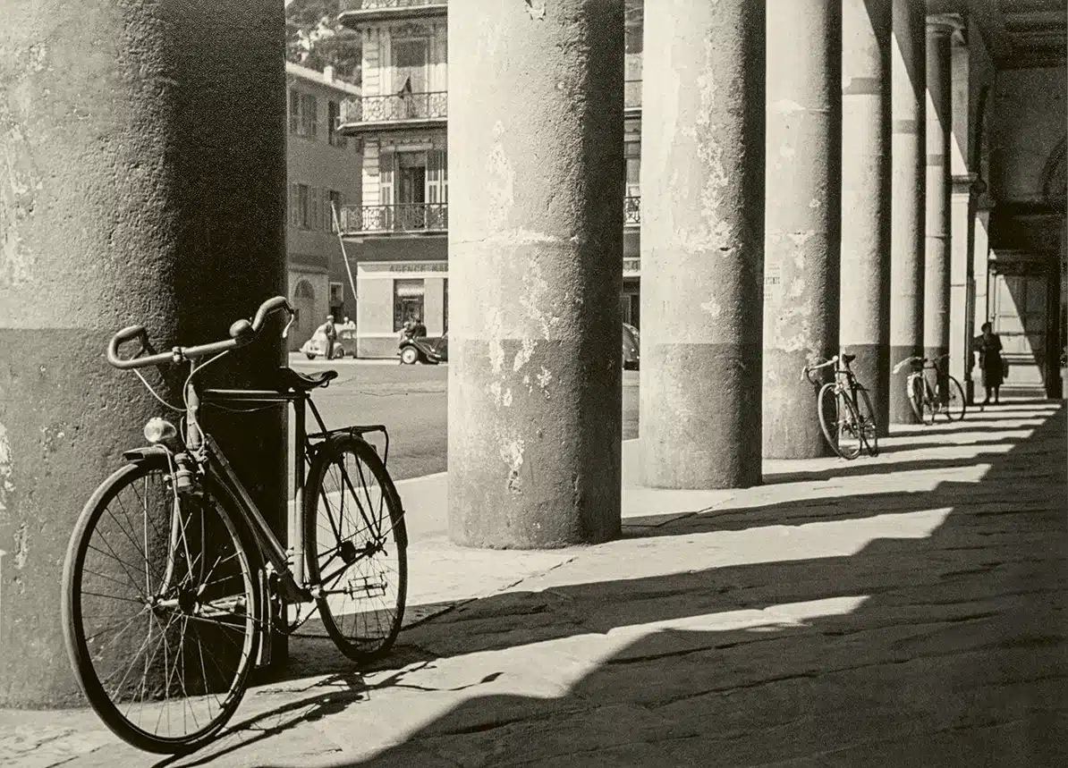 Joaquín Tusquets de Cabirol Bicycle leaning against a stone column beneath a porticoed gallery.