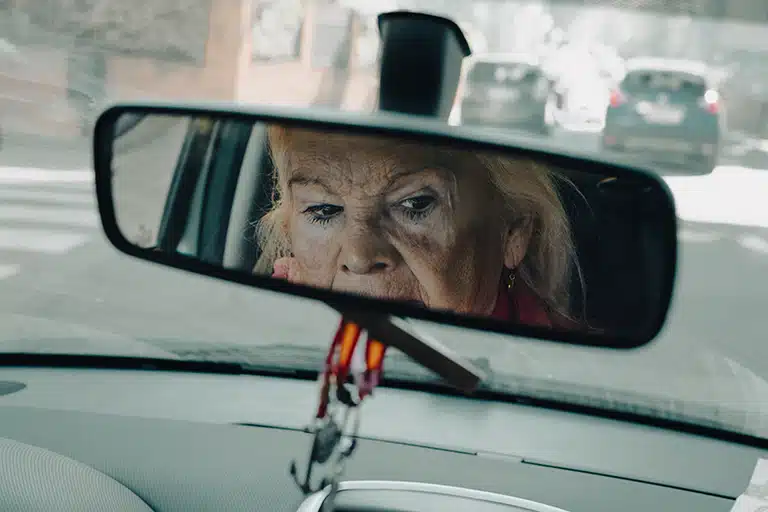 Mirada de una mujer mayor reflejada en el retrovisor de un coche