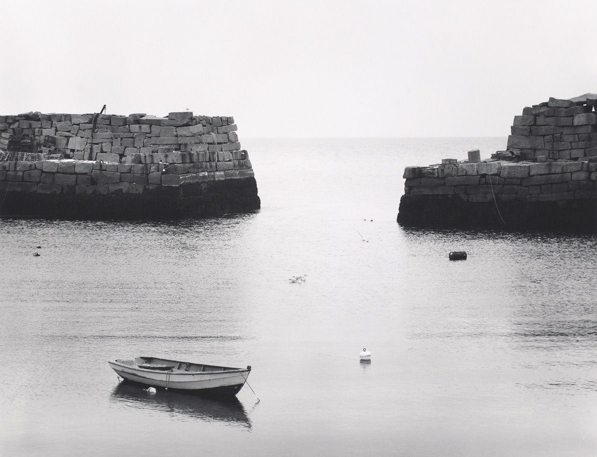 Minor White Boat on calm water between stone walls in black and white