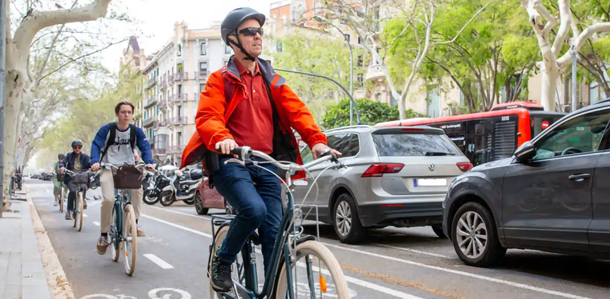 Ciclistas circulando por un carril bici en una avenida urbana.