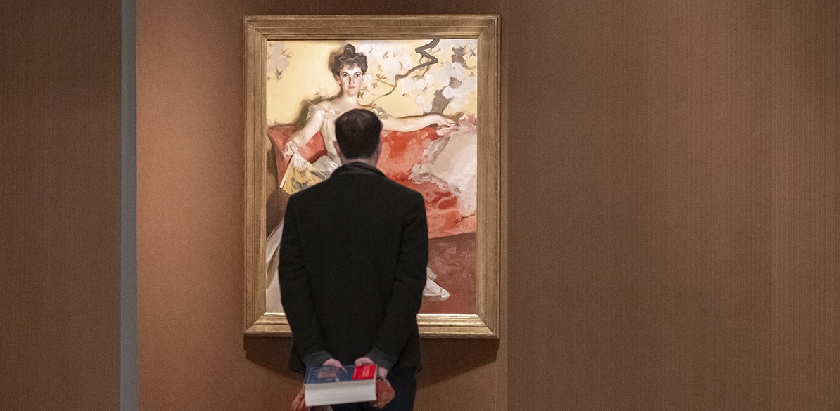 Visitante contemplando un retrato femenino en una exposición de Fundación Mapfre