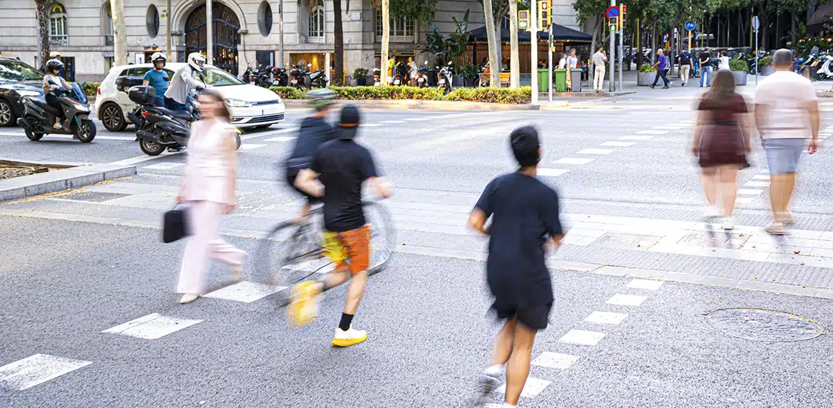 Cruce urbano con peatones, bicicleta y motos en movimiento