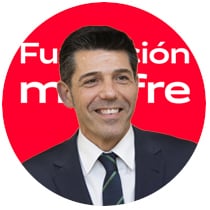 Circular corporate portrait of a smiling man wearing a dark suit, white shirt, and navy blue tie, against a red background with part of the Fundación Mapfre logo in white.