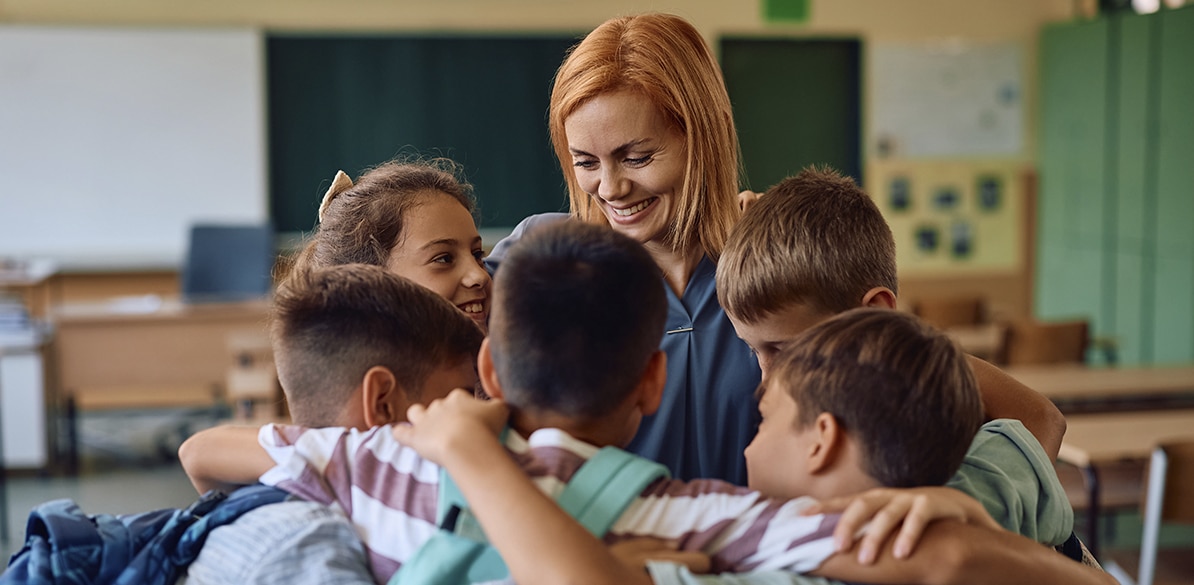 Docente junto a un grupo de estudiantes en un aula escolar durante una actividad colaborativa