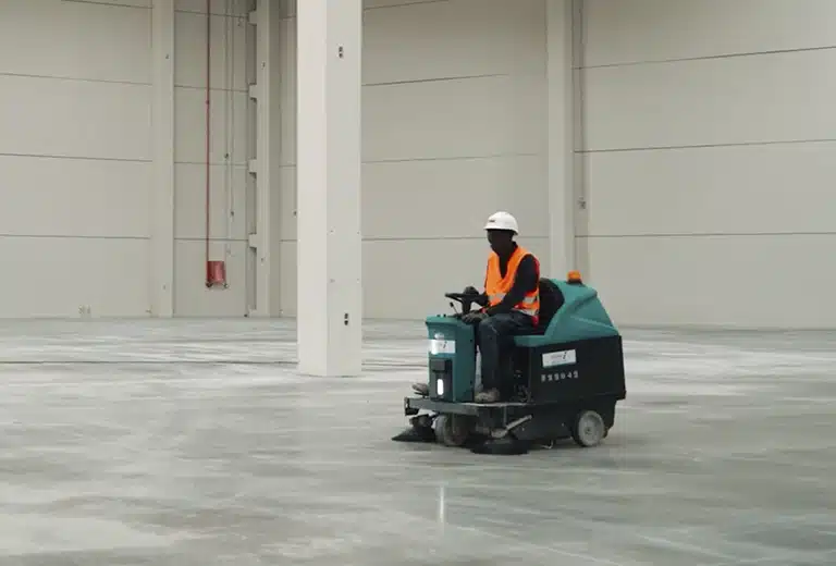 Trabajador conduciendo una máquina de limpieza industrial.