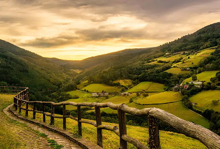 A green valley with wooden fences at sunset in the rural countryside of Asturias