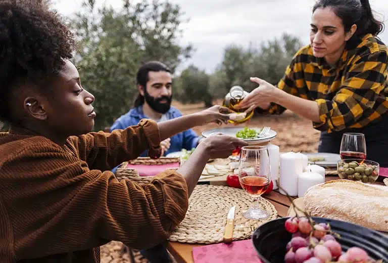 COCEMFE Group of people providing and sharing food outdoors in a rural setting, surrounded by fields and nature, promoting community.