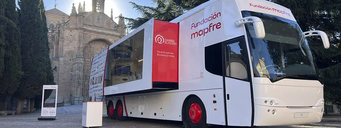 Autobús Solidario de la iniciativa Cambia el filtro de Fundación Mapfre, estacionado frente a un edificio histórico durante su recorrido por España
