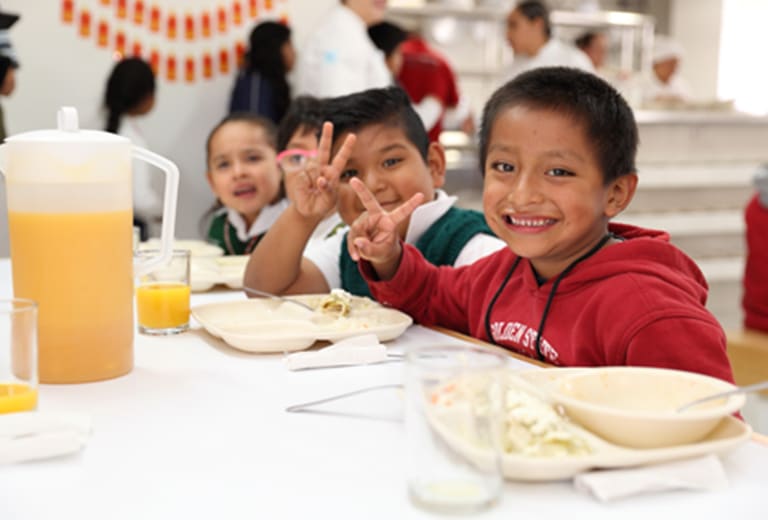 Infancia Niños disfrutando de una comida en un entorno educativo.