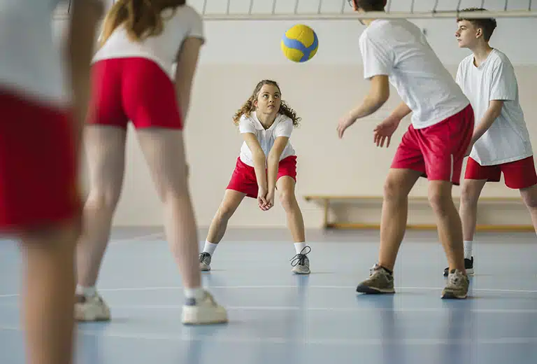Grupo de niñas de educación secundaria juagando un partido de voleibol.