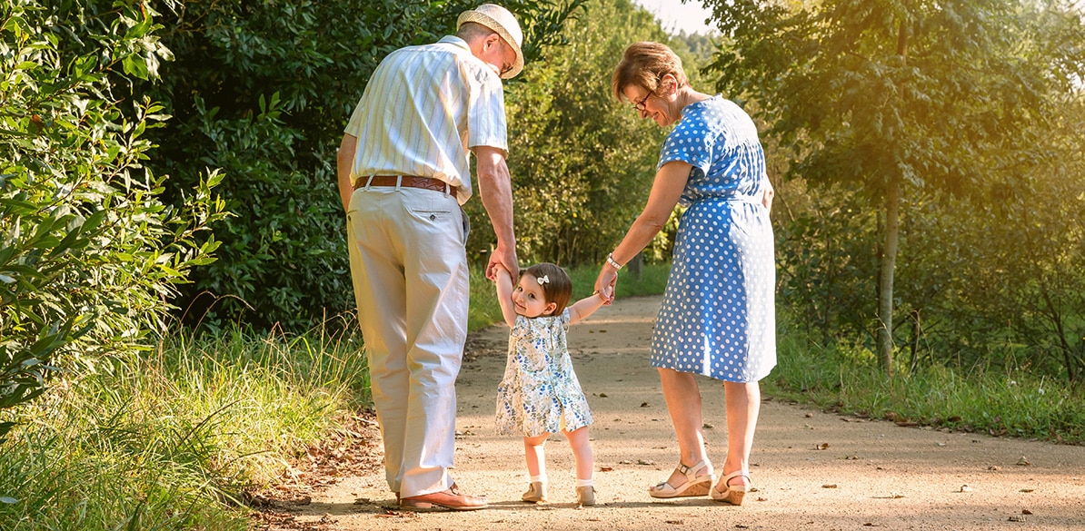 Un abuelo y una abuela paseando con su nieta por el campo.
