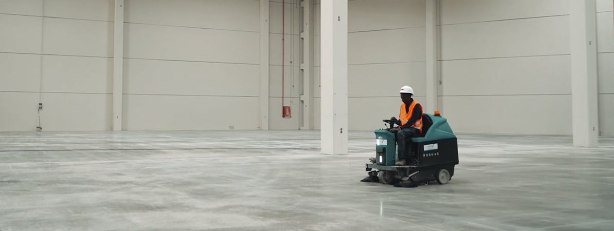 Empresas y entidades sociales Trabajador conduciendo una máquina de limpieza industrial.