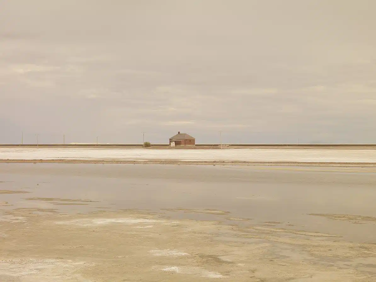 José Guerrero Paisaje con salinas blancas y una pequeña casa en el centro de un horizonte amplio, en tonos suaves, principalemtne grises y sepias. Fotografía Casa cerca de Wendover, del fotógrafo José Guerrero.